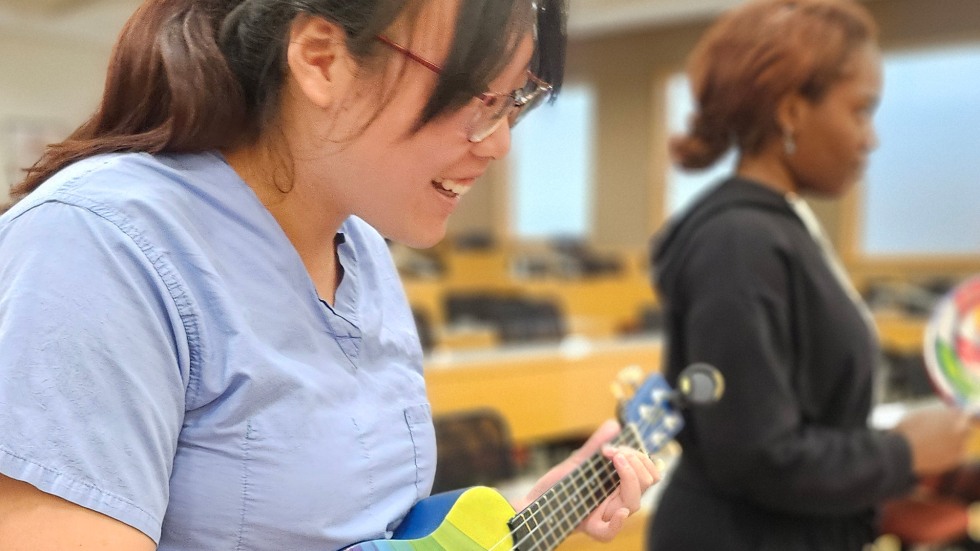 student smiling with a ukulele
